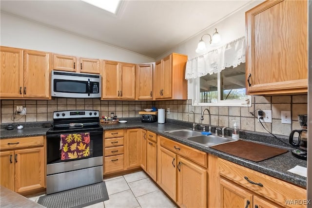 kitchen featuring lofted ceiling, dark countertops, stainless steel appliances, and a sink