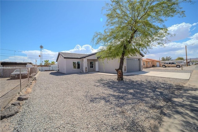 view of front of home featuring a garage, fence, driveway, and stucco siding