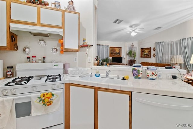 kitchen featuring white gas range oven, visible vents, white cabinets, under cabinet range hood, and a sink