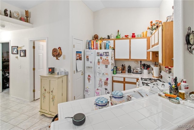 kitchen with lofted ceiling, white appliances, tile countertops, and light tile patterned floors