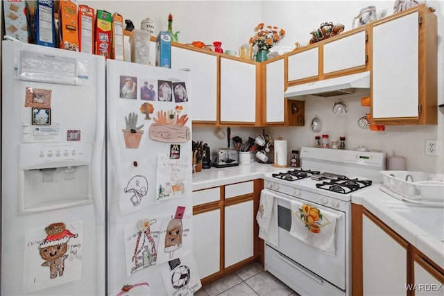 kitchen featuring light countertops, light tile patterned flooring, white cabinets, white appliances, and under cabinet range hood