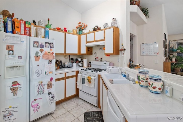 kitchen with tile countertops, white cabinets, a sink, white appliances, and under cabinet range hood