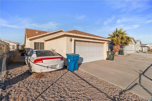 view of home's exterior with a garage, fence, driveway, and stucco siding