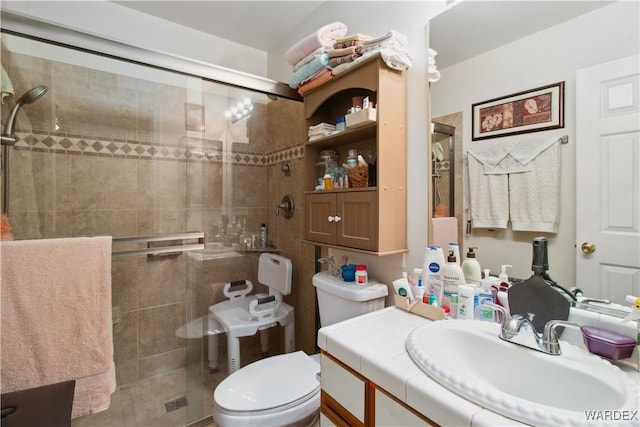 bathroom with toilet, a stall shower, and vanity