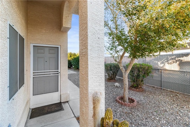 doorway to property with a patio, fence, and stucco siding