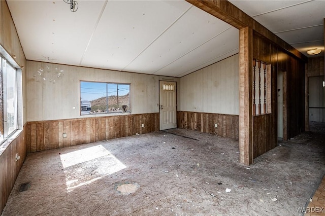 unfurnished room with wood walls and visible vents
