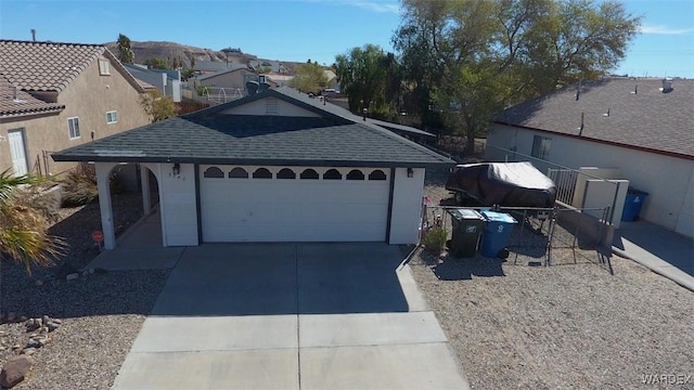 view of front facade with concrete driveway, roof with shingles, fence, and an attached garage