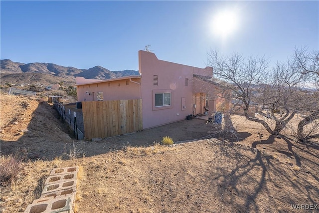 view of home's exterior featuring fence, a mountain view, and stucco siding