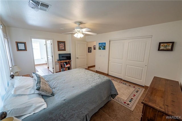 bedroom with light tile patterned floors, ceiling fan, a closet, and visible vents