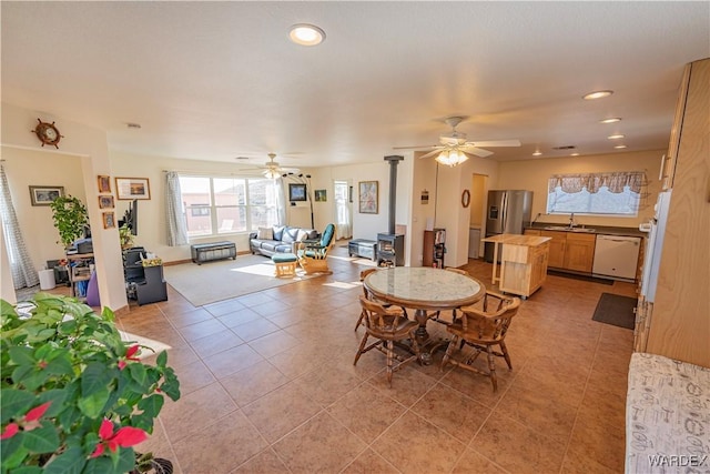 dining area featuring a wood stove, light tile patterned floors, a ceiling fan, and recessed lighting