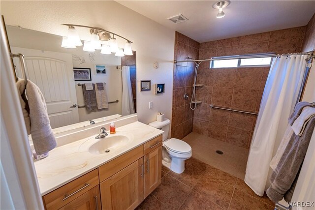 bathroom featuring toilet, a stall shower, vanity, and visible vents