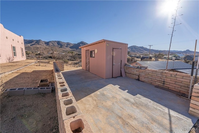 exterior space with an outbuilding, a storage shed, fence, and a mountain view