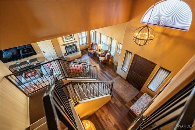 foyer featuring a glass covered fireplace, dark wood-style floors, stairway, a high ceiling, and a chandelier