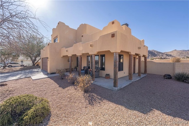 back of house featuring a patio area, stucco siding, fence, and a mountain view