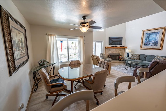 1800 Clubhouse Dr Unit D41, Bullhead City, AZ 86442 - dining room featuring light wood finished floors, a stone fireplace, ceiling fan, and a textured ceiling