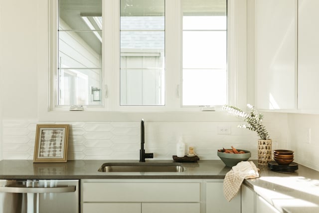 bar with stainless steel dishwasher, sink, white cabinetry, and tasteful backsplash