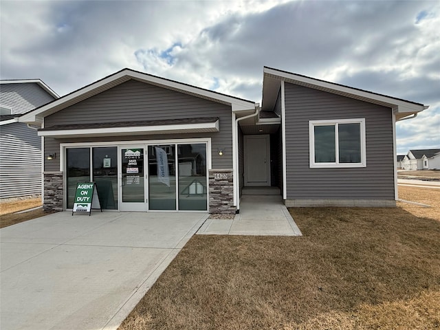 view of front of home with a garage, stone siding, driveway, and a front yard