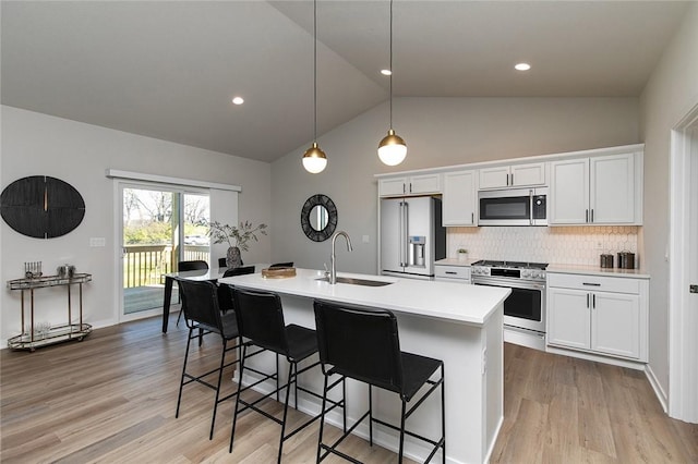 kitchen featuring white cabinets, hanging light fixtures, sink, an island with sink, and appliances with stainless steel finishes