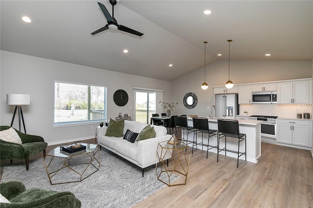 living room featuring ceiling fan, light hardwood / wood-style floors, lofted ceiling, and sink