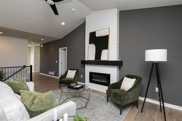 living room with wood-type flooring, a large fireplace, and lofted ceiling