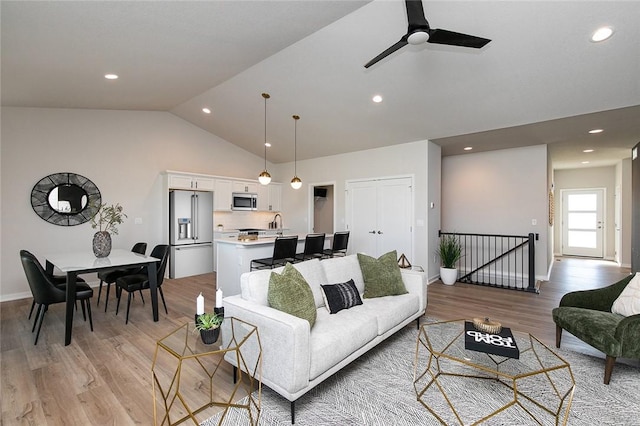 living room with light hardwood / wood-style floors, ceiling fan, and lofted ceiling