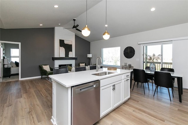 kitchen featuring a kitchen island with sink, sink, vaulted ceiling, stainless steel dishwasher, and white cabinetry