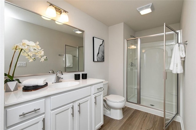 bathroom featuring hardwood / wood-style floors, vanity, toilet, and walk in shower