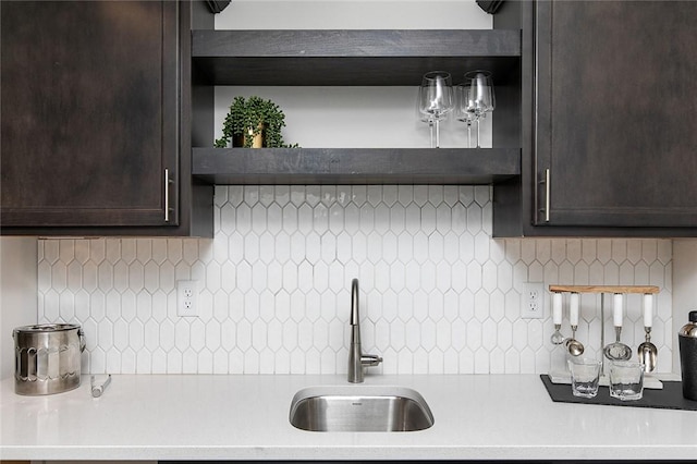 kitchen featuring backsplash, dark brown cabinetry, and sink