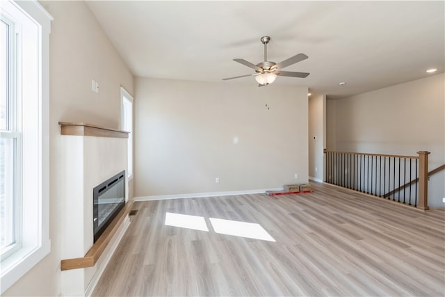 unfurnished living room featuring ceiling fan and light wood-type flooring