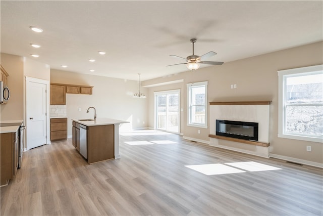 kitchen with light hardwood / wood-style flooring, an island with sink, ceiling fan with notable chandelier, and a wealth of natural light