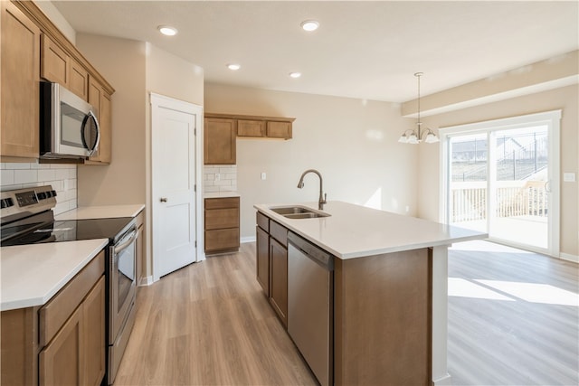 kitchen with sink, light hardwood / wood-style floors, stainless steel appliances, tasteful backsplash, and a notable chandelier