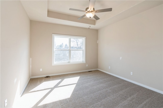 carpeted empty room featuring a tray ceiling and ceiling fan