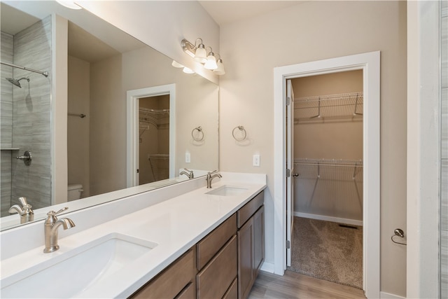 bathroom with a shower, hardwood / wood-style floors, toilet, and dual vanity