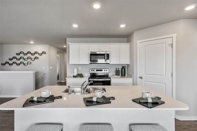 kitchen with a kitchen bar, sink, stainless steel appliances, and a center island with sink