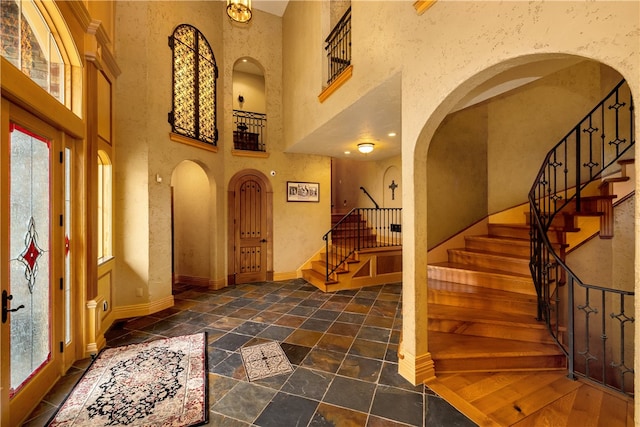 foyer featuring a high ceiling, dark tile floors, and a healthy amount of sunlight