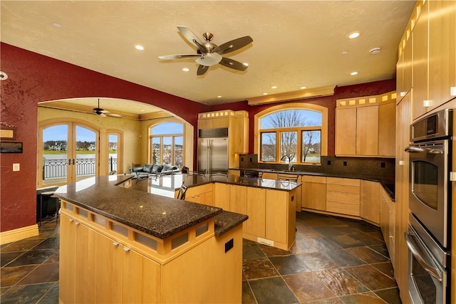 kitchen featuring french doors, an island with sink, dark tile floors, and appliances with stainless steel finishes