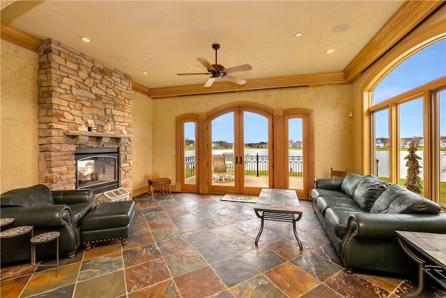 living room with a stone fireplace, french doors, a healthy amount of sunlight, and a water view