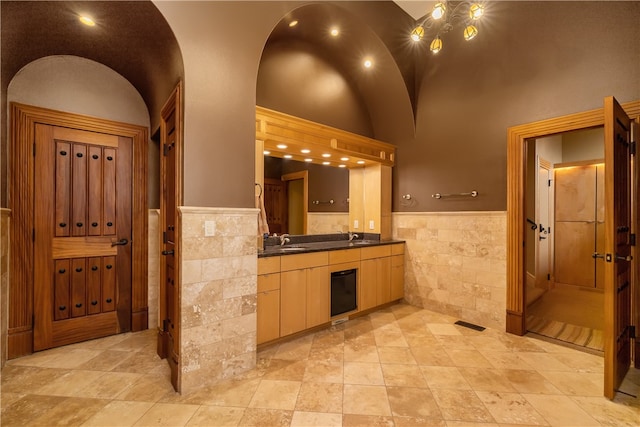 kitchen with light tile flooring, tile walls, a towering ceiling, and sink