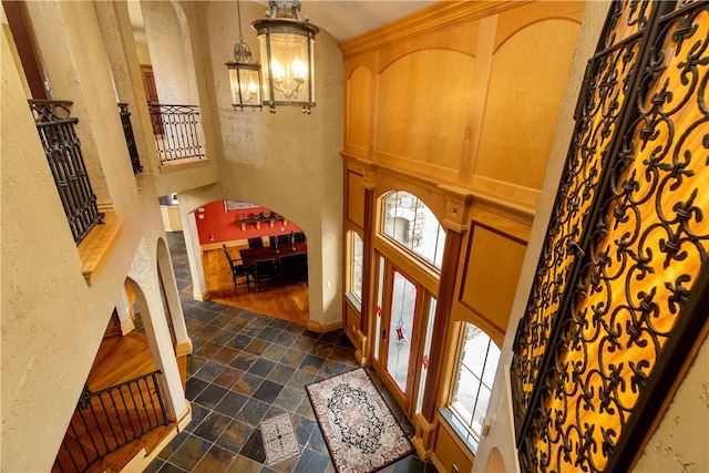 tiled entryway with a notable chandelier and a high ceiling