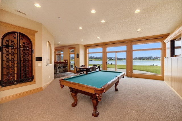 game room with light carpet, billiards, a textured ceiling, and a water view