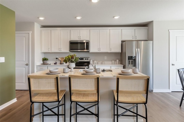 kitchen with white cabinetry, a breakfast bar area, an island with sink, and appliances with stainless steel finishes