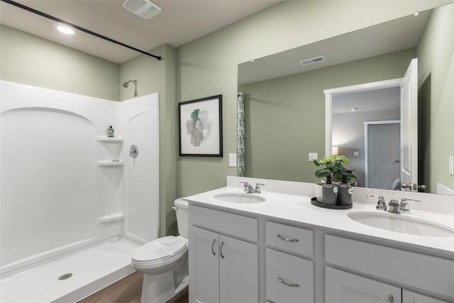 bathroom featuring vanity, hardwood / wood-style flooring, a shower, and toilet