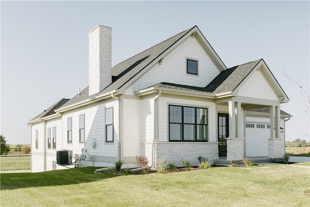 view of front of home featuring central air condition unit, a front yard, and a garage