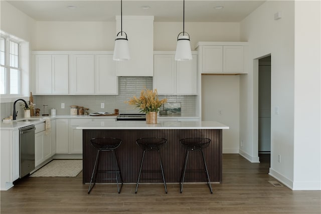 kitchen with a kitchen island, dishwasher, hanging light fixtures, sink, and white cabinets