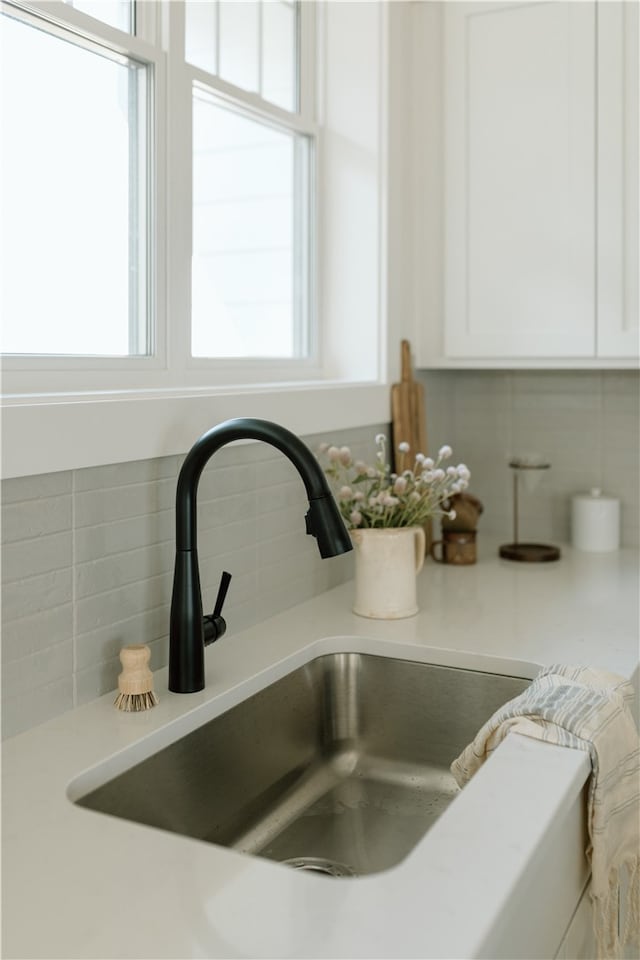 room details with sink, white cabinetry, and backsplash