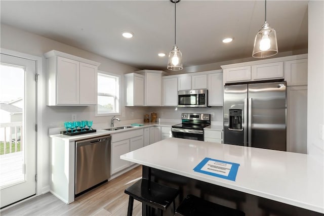 kitchen with white cabinets, pendant lighting, sink, and stainless steel appliances