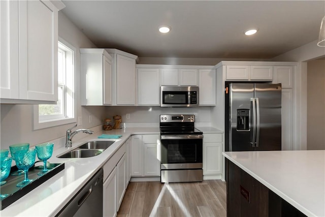 kitchen with white cabinets, sink, light wood-type flooring, and stainless steel appliances