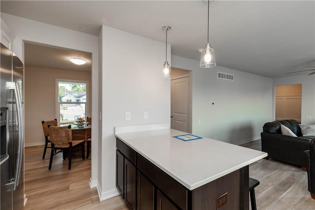 kitchen featuring ceiling fan, stainless steel fridge with ice dispenser, decorative light fixtures, dark brown cabinets, and light wood-type flooring