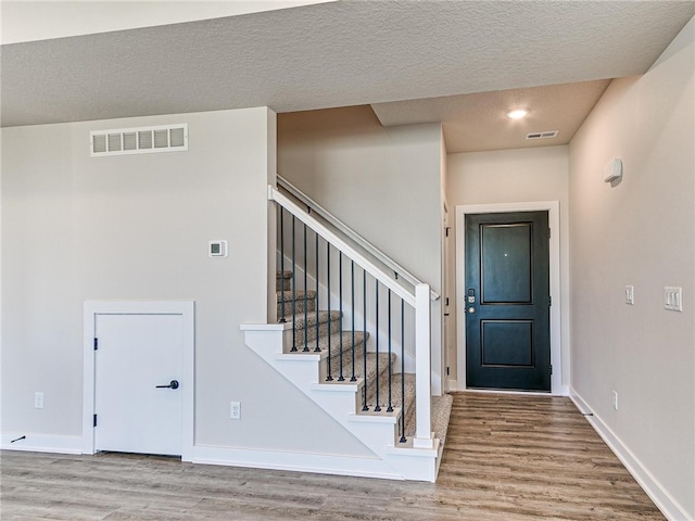 entryway with light hardwood / wood-style flooring and a textured ceiling