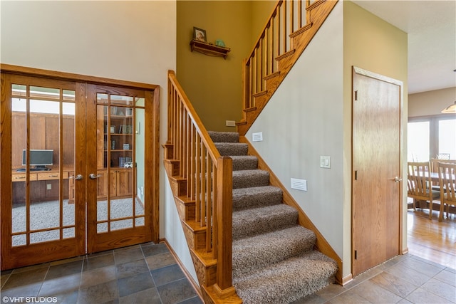 stairs with french doors, hardwood / wood-style flooring, and a wealth of natural light